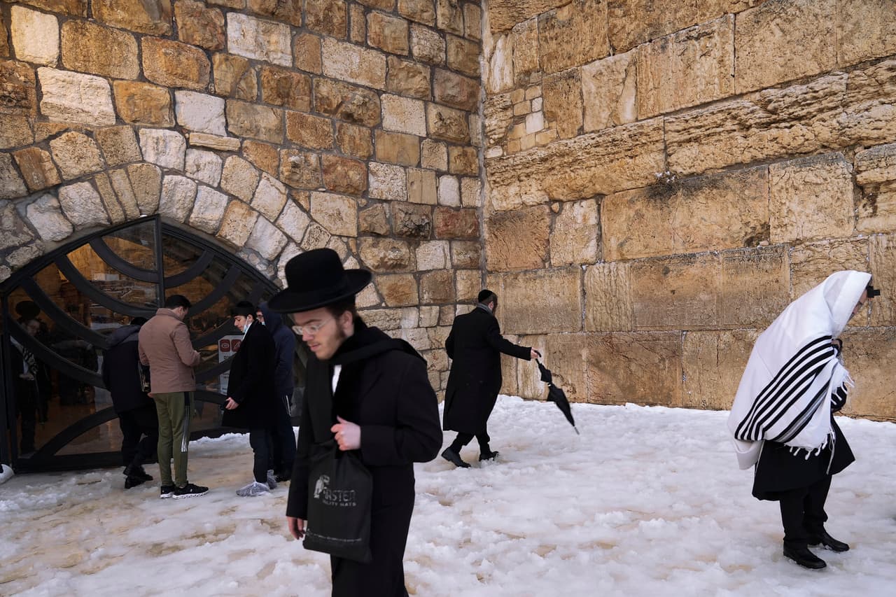 Un grupo de judíos ortodoxos caminan sobre el suelo cubierto de nieve en el Muro Occidental, uno de los lugares sagrados de esta religión en la Ciudad vieja de Jerusalén.
<br>