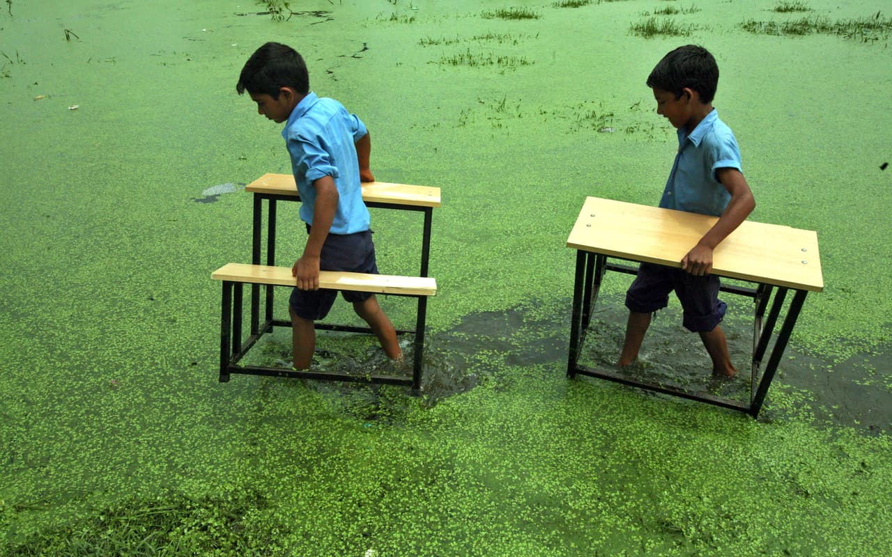 <b>India.</b> Estudiantes de la escuela primaria llevan sus bancos después de que su escuela fue inundada por las fuertes lluvias en la aldea de Bassi Kalan. 10 de agosto de 2011.