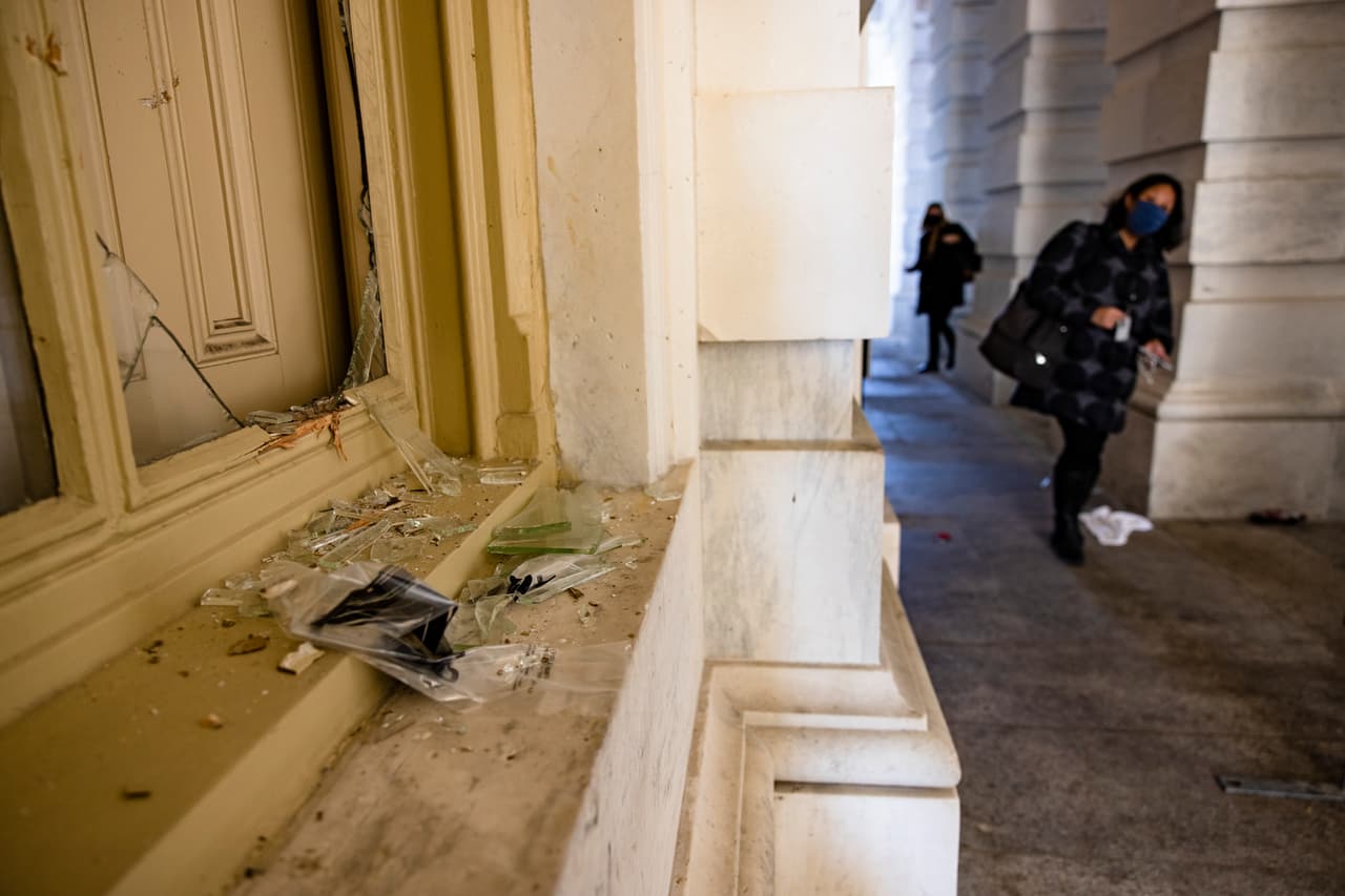 Personal del Congreso junto a una de las ventanas exteriores rotas por los manifestantes.