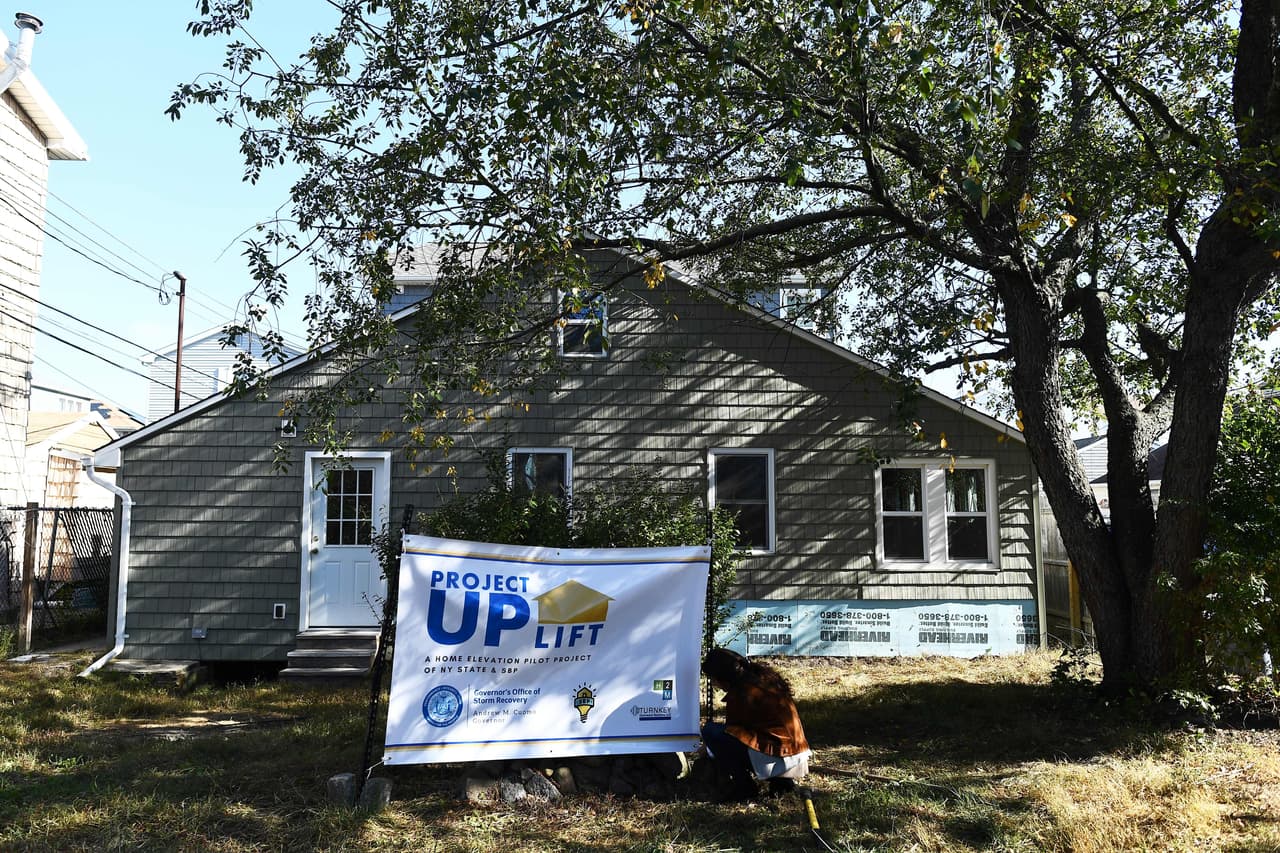 SBP's Alana Tornello sets up a banner in the yard of a home which is being prepared for Project UPLIFT, a $7.5 million home elevation pilot program, in Brooklyn, New York, on October 27, 2017. Five years after storm Sandy ravaged New York, members of the non-profit organization SBP, a disaster recovery organization founded to help rebuild Louisiana in the aftermath of Hurricane Katrina and its partners are still working to fix homes in hurricane affected area in New York. / AFP PHOTO / Jewel SAMAD (Photo credit should read JEWEL SAMAD/AFP/Getty Images)