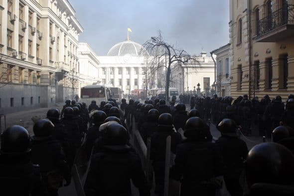 La policía ucraniana cercó hoy a los manifestantes en el corazón de las protestas opositoras de la plaza de la Independencia de Kiev (Maidán), tras una jornada en la que murieron 14 personas en los disturbios que estallaron en la capital. Víktor "Yanukóvich se ha convertido en un presidente sangriento", aseguró hoy el dirigente opositor Vitali Klitschkó en un llamamiento a los países democráticos para que intervengan en Ucrania y frenen la violenta confrontación. Según se acercaba la medianoche, los temidos Berkut, el destacamento antidisturbios, estrechaban el cerco en torno a los miles de manifestantes concentrados en el Euromaidán, bastión de las protestas desde el pasado 21 de noviembre. "Los extremistas de la oposición han cruzado la línea roja; matan a inocentes en la calles de la capital de Ucrania, vejan a mujeres, queman edificios y automóviles. Y si los disturbios continúan, nos veremos obligados a actuar con firmeza", rezaba el ultimátum del Servicio de Seguridad y el Ministerio del Interior de Ucrania. Advierten a los americanos que se queden dentro de las casas y de nuevo se sienten explosiones en la ciudad.