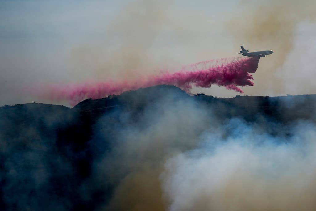Un avión lanzando retardante sobre las llamas del incendio Palisades.