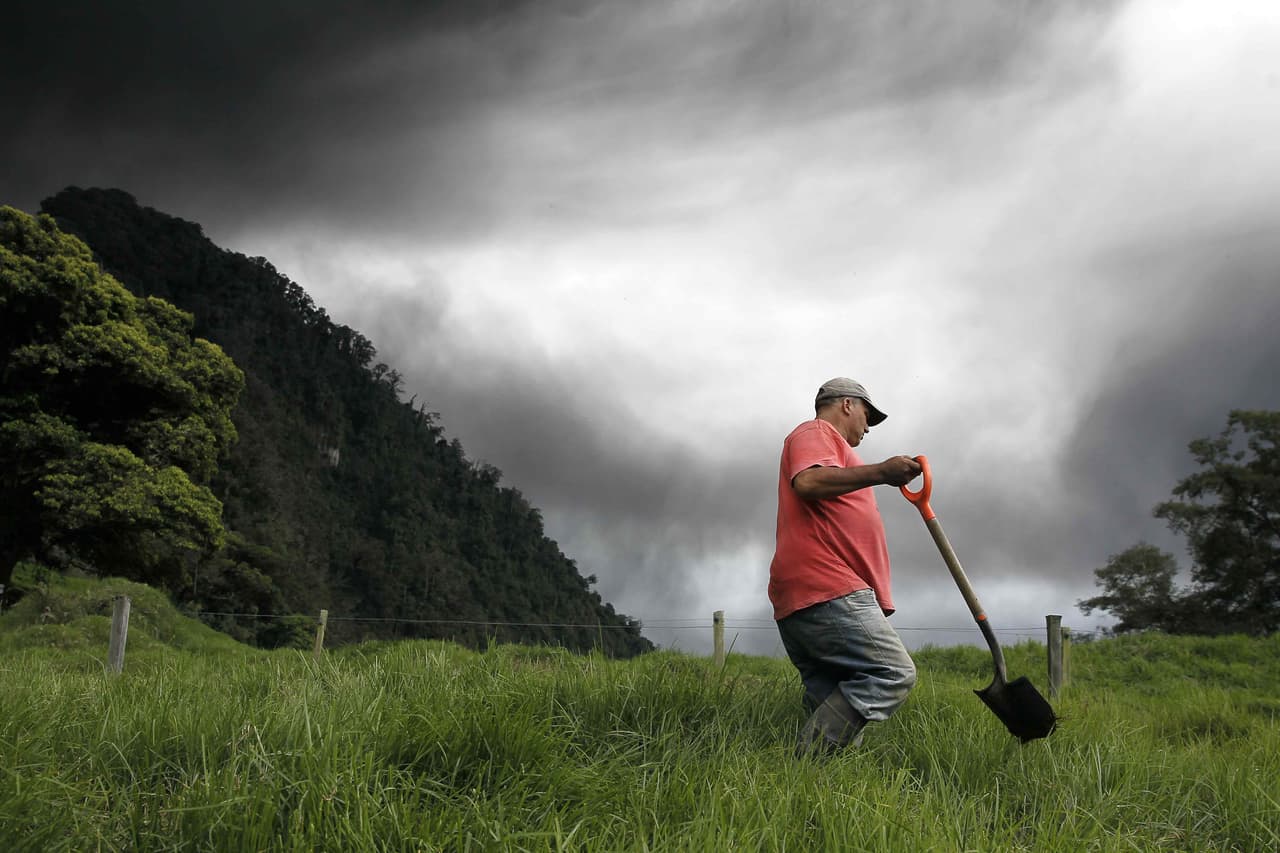 Un agricultor trabaja cerca de la ceniza expulsada por el volcán. La Comisión Nacional de Emergencias de Costa Rica recomendó poner en práctica procesos de protección de la salud, especialmente para aquellas personas que tienen problemas en las vías respiratorias