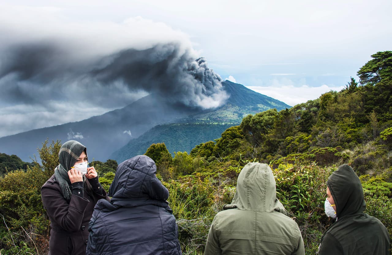 Algunas personas se reúnen a ver la erupción volcánica. La Comisión Nacional de Emergencias aconsejó a los residentes llevar mascarillas y ropa ajustada para proteger los pulmones y la piel