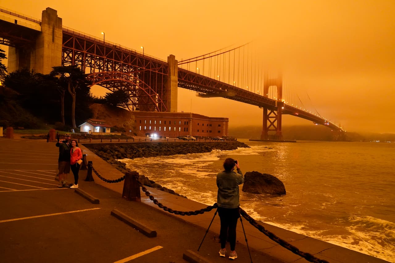 Transeúntes toman fotos del puente Golden Gate bajo el cielo anaranjado por el humo por los incendios forestales. Alrededor del área de San Francisco y otras partes del norte de California el cielo enrojecido por el humo de los numerosos incendios forestales oscureció el firmamento, al punto que muchos mantuvieron las luces encendidas al mediodía.
<br>