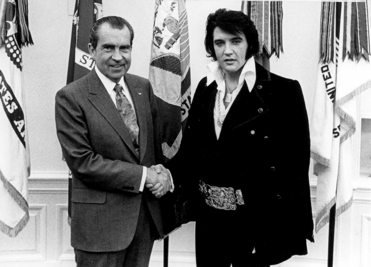Elvis Presley y Richard Nixon (1913-1994) dicen que son los nombres occidentales más conocidos en China. Jesucristo también, pero él no fue invitado a esta reunión en la Casa Blanca el 21 de diciembre de 1970. La presidencia de NIxon, entre 1969 y 1974, terminó con la guerra de Vietnam, con el servicio militar obligatorio, creó la Agencia Nacional Ambiental, presidió la llegada del hombre a la Luna y espió y hostigó a sus opositores políticos con la ayuda del FBI, la CIA y el IRS. Este escándalo, conocido como Watergate, por el nombre del edificio donde el Partido Demócrata tenía sus oficinas. Allí, la madrugada del 17 de junio de 1972, cinco miembros de la CIA fueron arrestados por entrar a las instalaciones de manera irregular para instalar micrófonos y espiar a los rivales políticos de Nixon. Estas revelaciones lo llevaron a renunciar después de un juicio político.