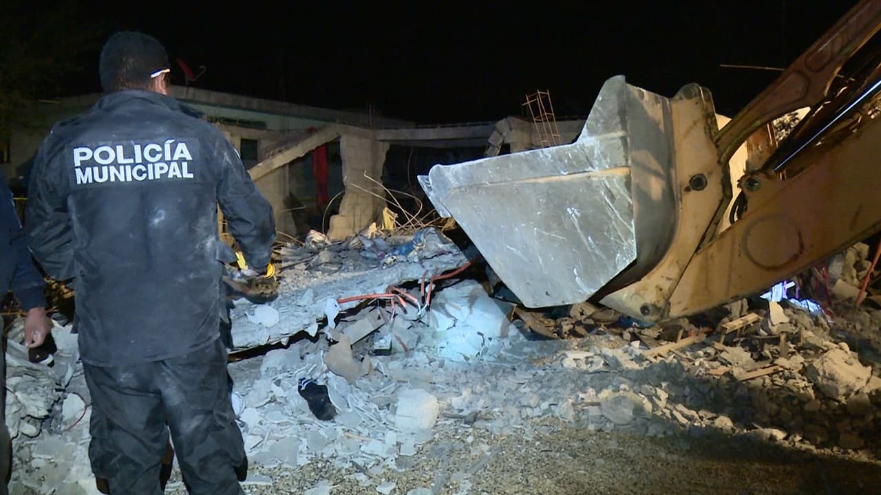 Un grupo de personas busca con maquinaria víctimas entre los escombros