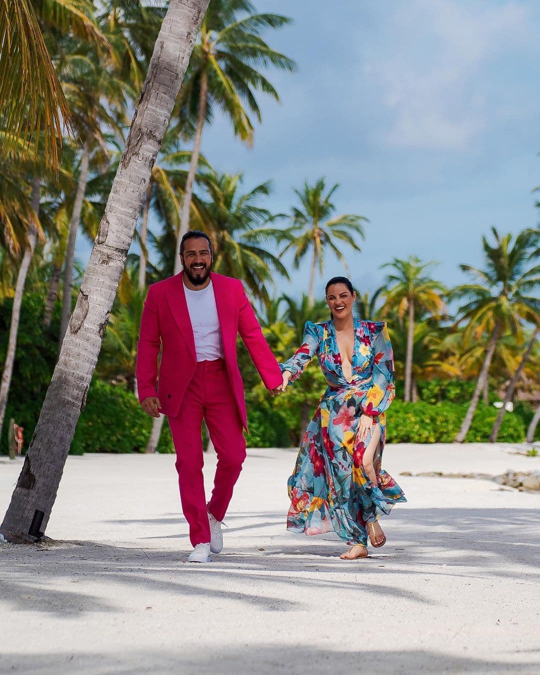 Maite Perroni lució un colorido vestido de estilo tropical en el que destacó el escote en 'v' hasta la cintura. Para la sesión de fotos en su luna de miel, su esposo portó un traje rojo que combinaba con su 'outfit'.
