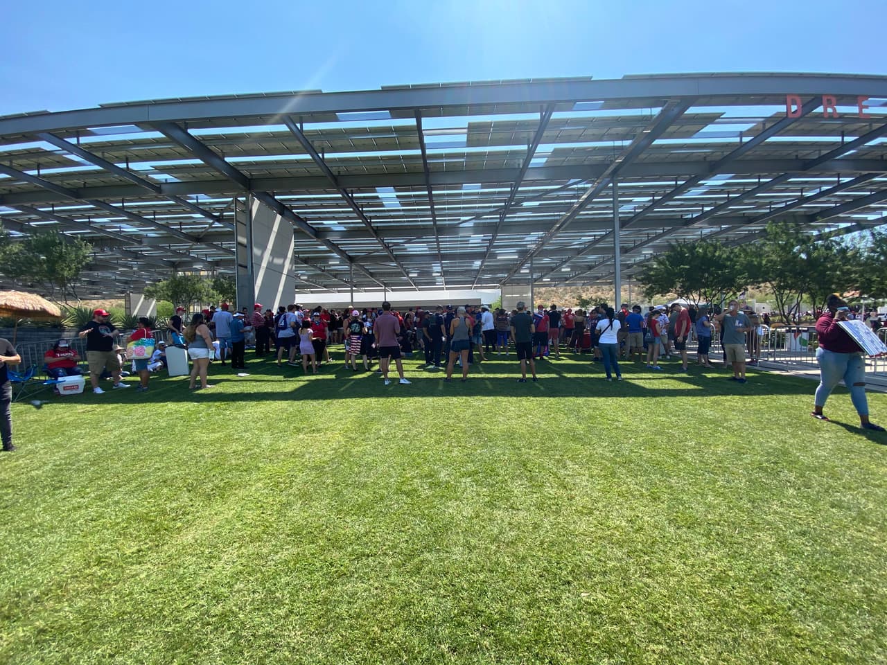 Decenas de personas esperan la llegada del presidente mientras un techo los cubre del calor que azota a Phoenix.