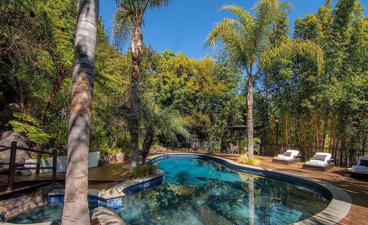 La piscina, inspirada en una laguna, se encuentra rodeada por pisos de madera y jardines tropicales.