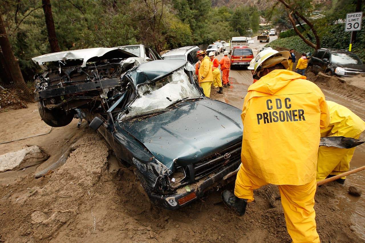 LA CANADA-FLINTRIDGE, CA - FEBRUARY 6: A crew of inmate firefighters from Azusa, California digs out cars that were swept away as debris flows damaged homes on February 6, 2010 in La Canada Flintridge, California. Large wildfires in 2008 and 2009 stripped the hills and mountains of vegetation, resulting in mud and debris flow danger as winter rains pass over foothill communities where thousands of people have been evacuated at times in recent weeks. The threat is particularly high near the San Gabriel Mountains above La Canada-Flintridge area which were denuded of natural flood-controlling vegetation by the 250-plus square mile Station. At least 40 homes have been severely damaged and 500 remain evacuated. (Photo by David McNew/Getty Images)