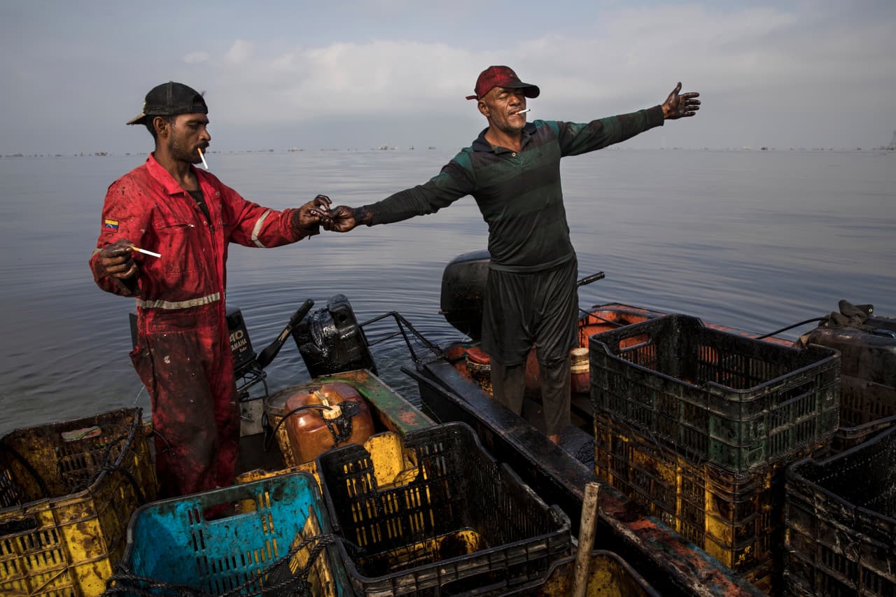 Pescadores de cangrejo con su ropa y equipo manchados de petróleo cerca de Cabimas. Expertos ambientales dicen que la contaminación petrolera en el lago comenzó en la década de 1930, cuando se cavó allí un canal para permitir la navegación de buques petroleros grandes. En poco tiempo entró agua salada de mar, lo que mató a parte de la fauna lacustre. Aparte de eso, se desarrolló la agricultura en la zona cercana al lago, lo que vertió fertilizantes a sus aguas y destruyó parte del ecosistema.