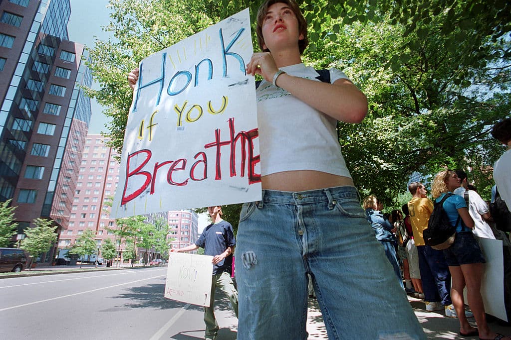 Una manifestante sostiene un cartel en un mitin el 19 de junio de 2001 frente al Centro Nacional de Sistemas de Transporte John A. Volpe en Cambridge, MA, donde el Departamento de Energía celebró una reunión pública sobre eficiencia energética y Programas de Energías Renovables.