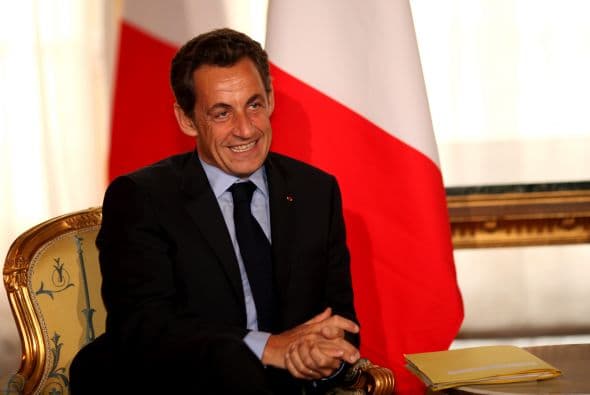Tras él aparece Nicolás Sarkozy, presidente de Francia.