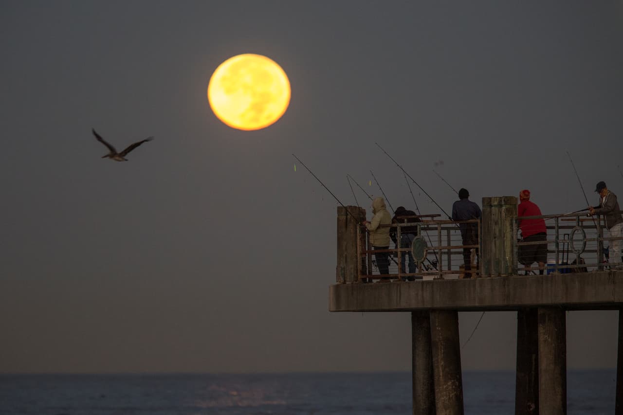 Pescadores de Redondo Beach, California, frente a la superluna antes de ocultarse en el pacífico, la mañana del 14 de noviembre.