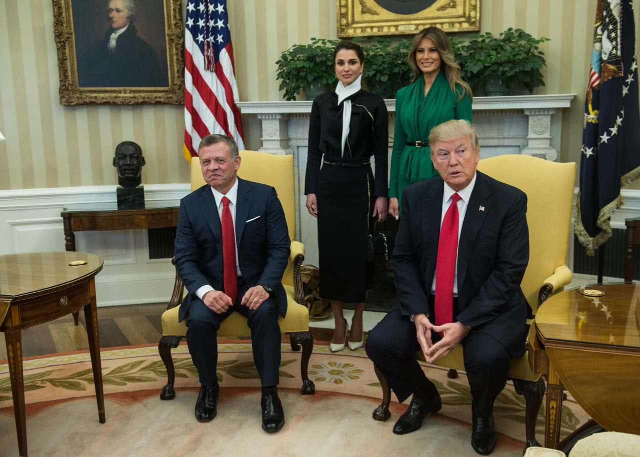 Cuando anfitriones e invitados entraron a la Oficina Oval y el rey y el presidente Donald Trump tomaron asiento, los vestidos de la reina y la primera dama dejaron de ser el tema de conversación. Fuera de lo esperado,
<b>las dos mujeres se pararon detrás de los mandatarios y posaron para la foto ahí en medio de las banderas de las dos naciones.</b> Un gesto inusual. Una foto inusual.