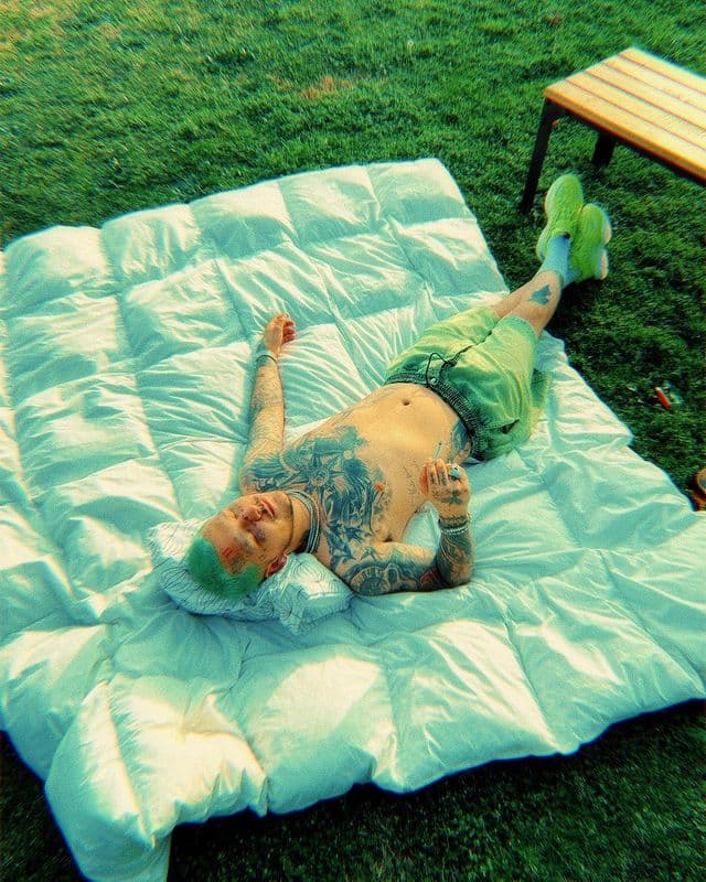 En la instantánea, Christian Nodal aparece acostado sobre una colchoneta, con los ojos cerrados y disfrutando el sol, pero destaca que ahora tiene el cabello de color verde claro. 
<br>