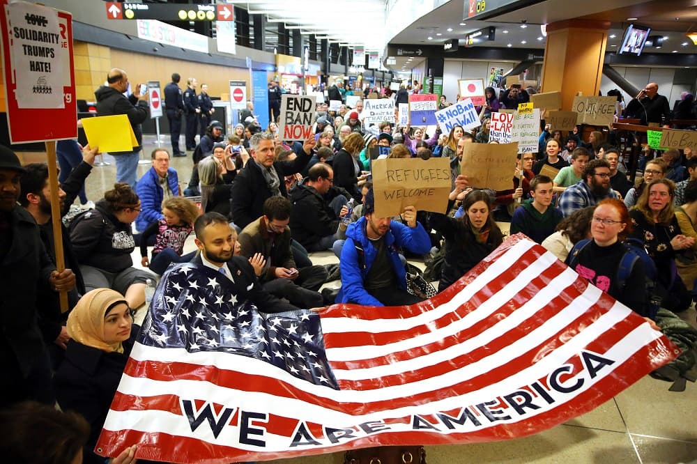 Manifestantes en el Seattle-Tacoma International Airport con una bandera donde se lee "Somo Amércia".