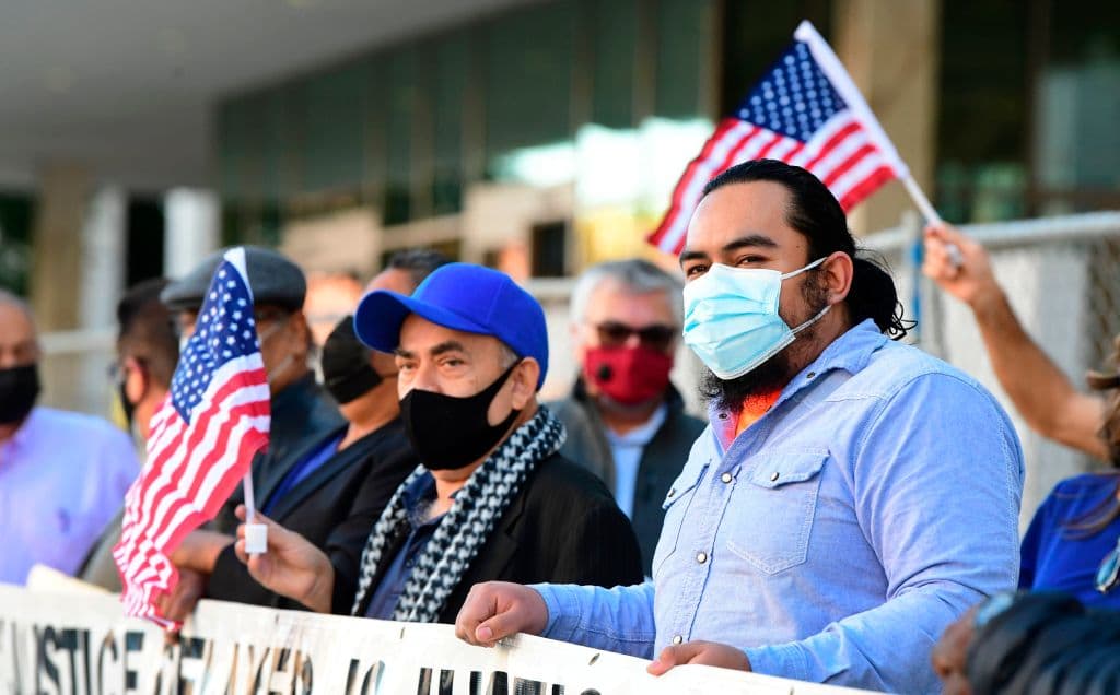 Immigration activists wave US flags during a rally outside the Federal Building in Los Angeles, California on January 14, 2021.