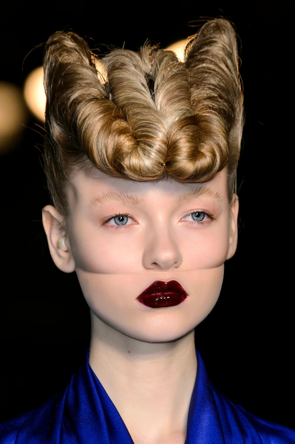 El maquillaje creado por 
<a href="https://www.instagram.com/thevalgarland/">Val Garland</a> para el desfile de 
<a href="http://www.vogue.com/fashion-shows/fall-2016-ready-to-wear/gareth-pugh">Gareth Pugh</a> está inspirado en 
<a href="http://www.imdb.com/character/ch0001399/">Hannibal Lecter</a>. Los ojos van sin maquillaje, mientras que los labios llevan con un tono vino brillante. Una especie de malla transparente que se sujeta en la parte trasera de la cabeza permite crear este extraño efecto que divide el rostro. Para evitar la incomodad, te recomiendo dar profundidad con ayuda de los correctores que usas para hacer el 
<i>contouring</i>.
<br>