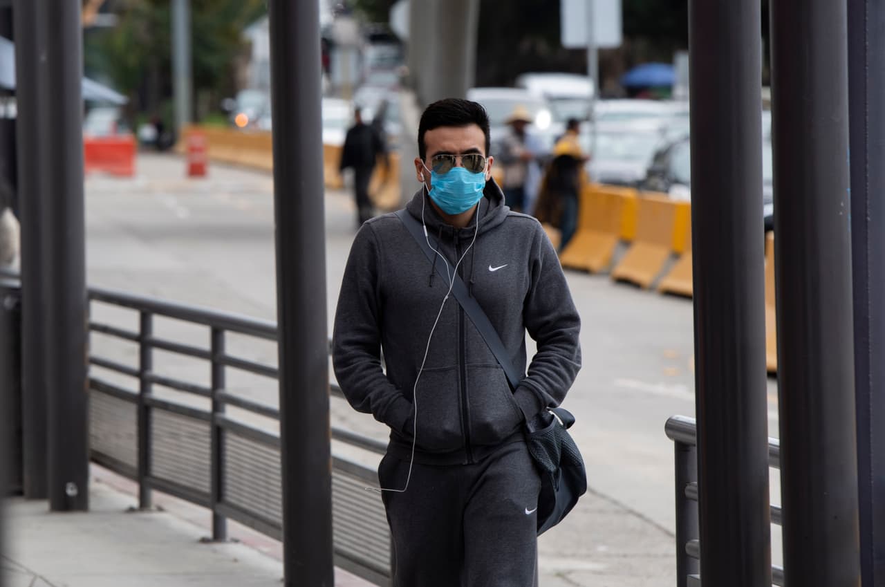 Un hombre con el rostro cubierto por una mascarilla camina por el puerto de San Ysidro, para cruzar a los Estados Unidos desde Tijuana . 
<br>