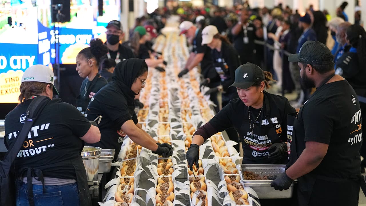 Voluntarios preparan sándwiches de filete de queso en un intento por batir un récord mundial Guinness durante el Día Nacional del Cheesesteak en el Aeropuerto Internacional de Filadelfia