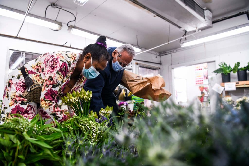 Con mascarilla, una clienta escoge flores en Miami, Florida, en la víspera de San Valentín. Morey Moss, el dueño del establecimiento, dijo que sus ventas se han recuperado tras un desastroso 2021 por el golpe de la pandemia.