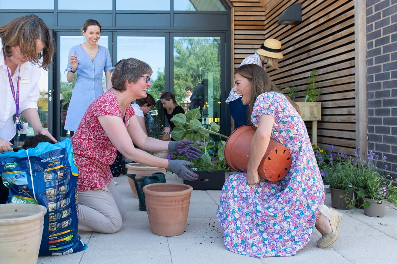 La duquesa de Cambridge se arrodilló en el suelo para ayudar a los niños y a las familias a sembrar plantas para el jardín del hospicio. 
<br>