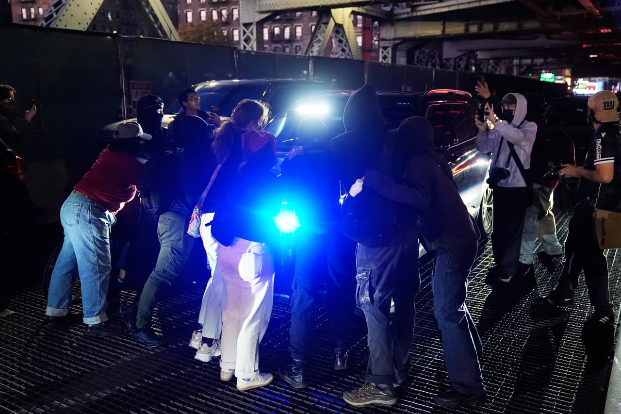 Unas personas impiden el paso de un automóvil cerca del lugar de un tiroteo el jueves 8 de octubre de 2026 en Nueva York.