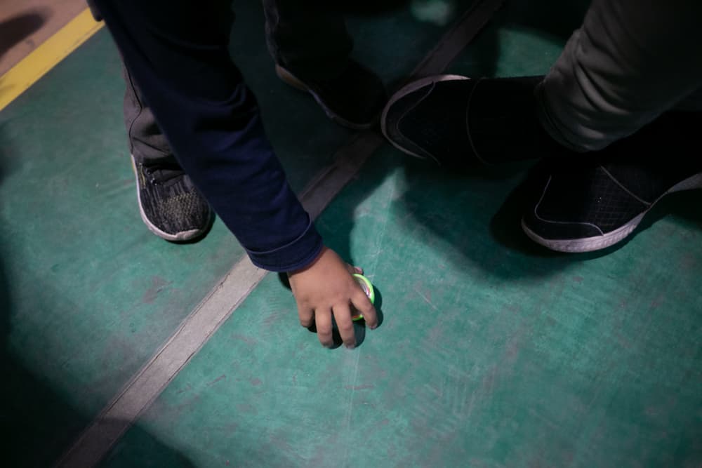 Santiago, el hijo menor de Yanci, juega junto a otro niño con un trompo que le regalaron en el albergue municipal instalado en el gimnasio 'Kiki Romero', en Ciudad Juárez.