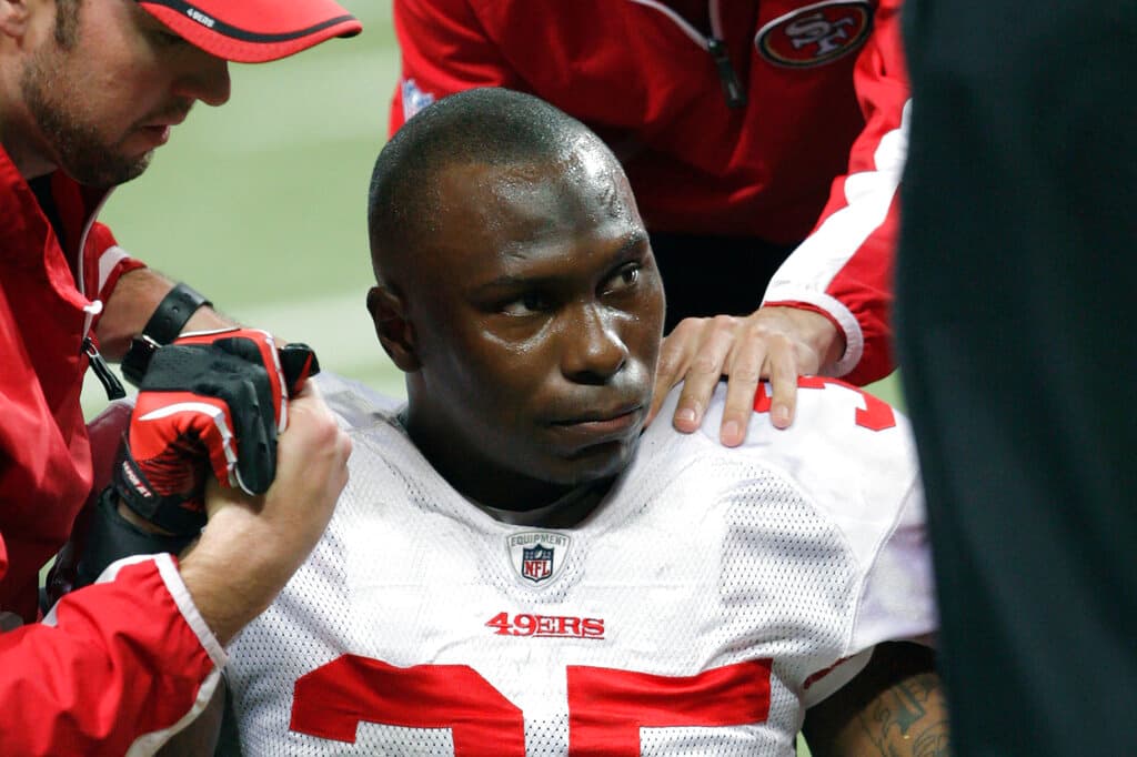 ARCHIVO - En esta foto del 26 de diciembre de 2010, el cornerback Phillip Adams (35) de los 49ers de San Francisco recibe atención por una lesión en la pierna izquierda en un partido de la NFL contra los Rams de San Luis. (AP Foto/Tom Gannam)