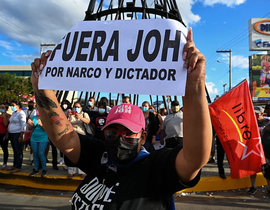 A woman holds a placard reading "JOH (Honduran President Juan Orlando Hernandez) Out" in Tegucigalpa on March 30, 2021 after Juan Antonio "Tony" Hernandez, brother of the president, was sentenced to life for drug trafficking offenses in New York.