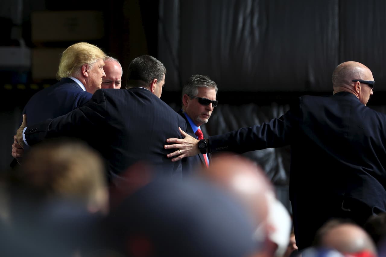 Secret Service agents surround U.S. Republican presidential candidate Donald Trump during a disturbance as he speaks at Dayton International Airport in Dayton, Ohio, March 12, 2016. REUTERS/Aaron P. Bernstein TPX IMAGES OF THE DAY - RTX28USH