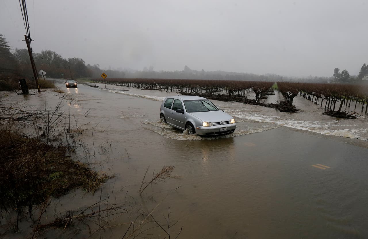 Un coche cruza la calle Green Valley Road en la ciudad de Graton, California, que se inundó este sábado por la llegada de una serie de tormentas.