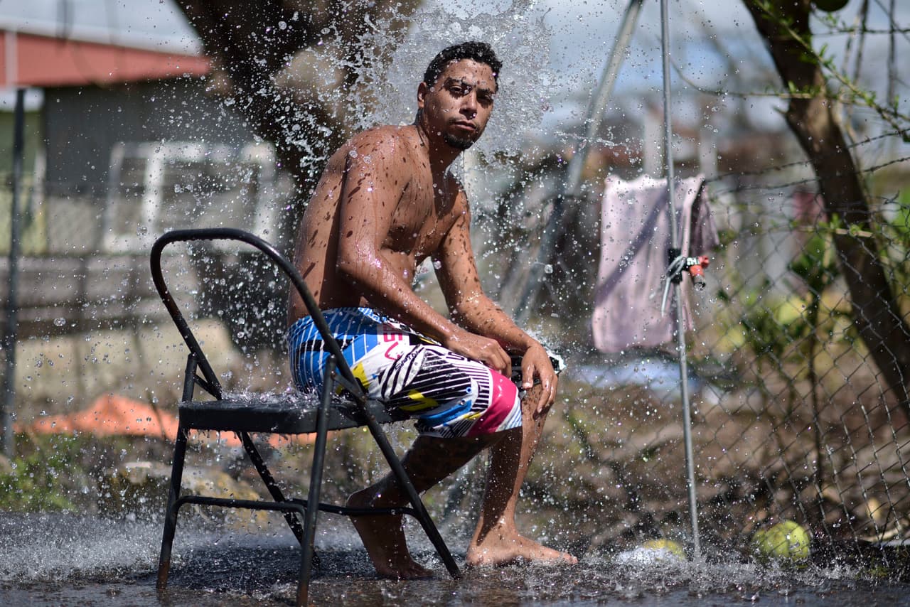 Jorge Ortiz, de 25 años, toma una ducha con agua potable a unl lado de la carretera en Santa Isabel, Puerto Rico.