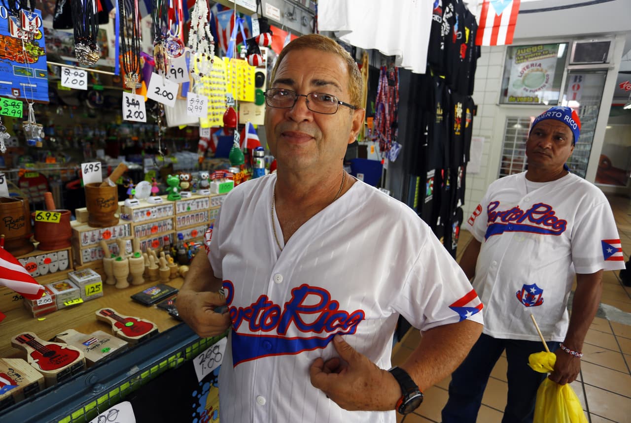 Eduardo Ruiz muestra su camiseta del equipo de béisbol puertorriqueño y su pelo teñido de rubio. (EFE)
