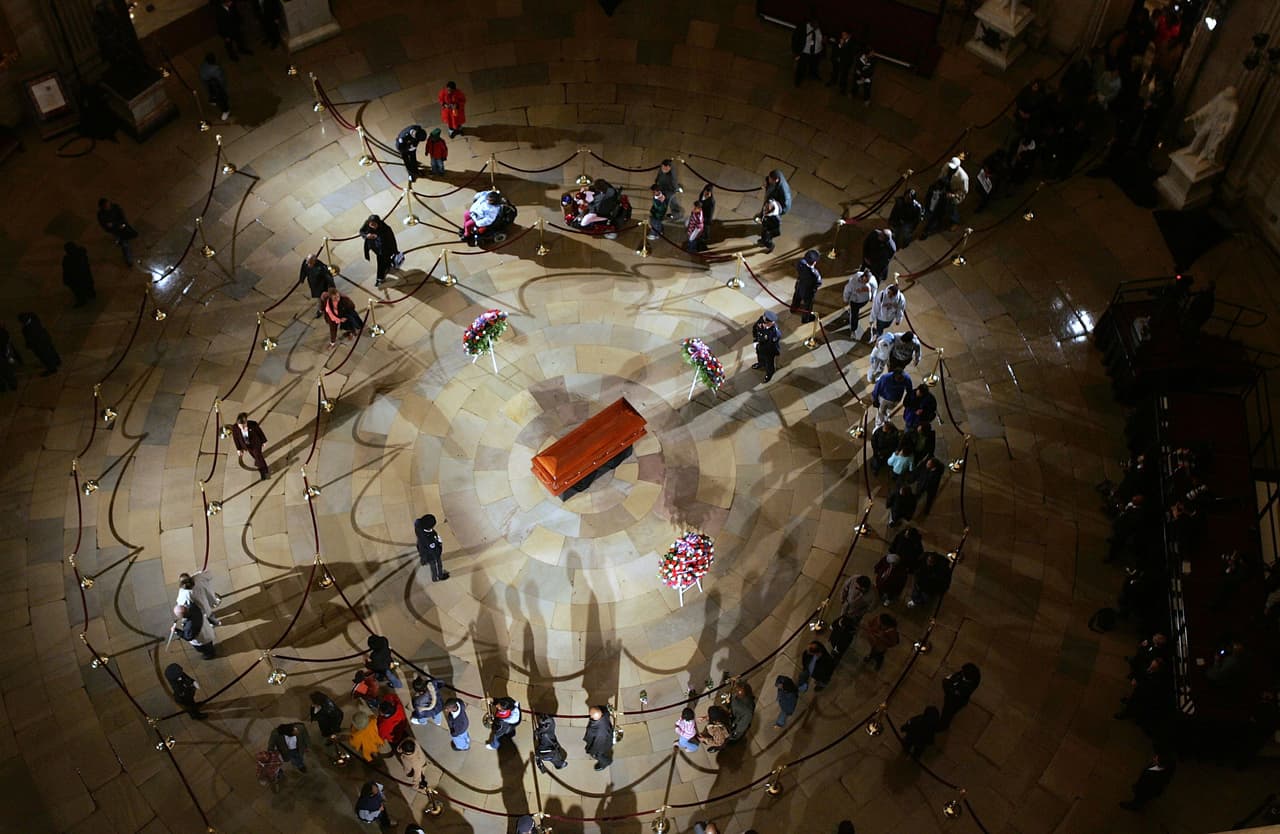 Los restos de Rosa Parks en la Rotonda del Capitolio, el 30 de octubre de 2005. Desde que comenzaron los eventos funerarios en el edificio del Congreso en 1852, Parks fue la persona número 31 en estar allí, y la primera que no fue funcionaria pública en ser honrada de esta manera. Fue la primera mujer y la segunda persona negra en recibir ese honor.