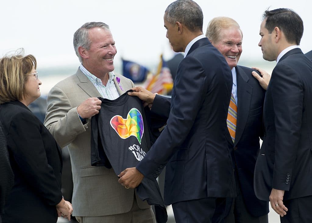 El alcalde de Orlando, Buddy Dyer, le muestra una camisa con los colores de orgullo gay al presidente Obama ante su llegada a la ciudad.