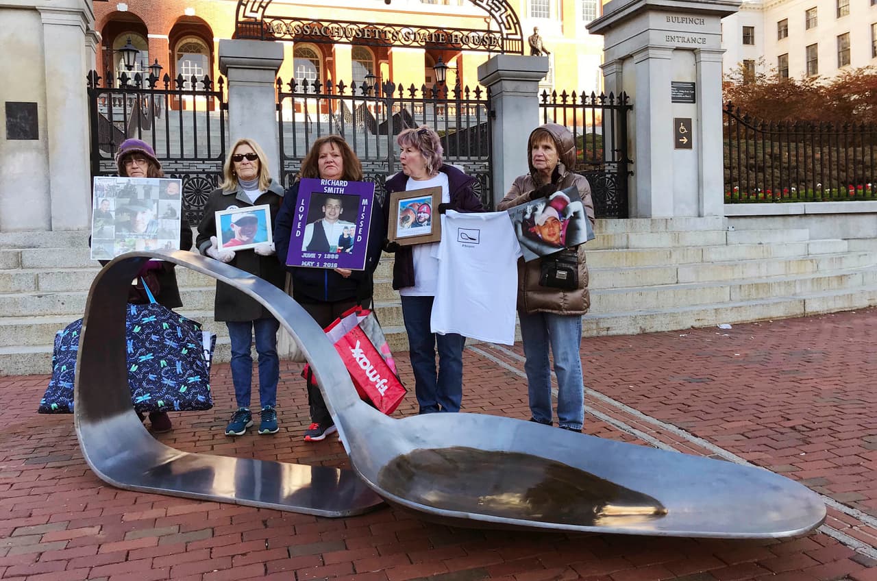 Madres y familiares de personas que perdieron la vida debido a una sobredosis posan al lado de una enorme cuchara de metal que simboliza el uso de opioides, a las afueras del Capitolio de Massachusetts, a finales del año pasado.