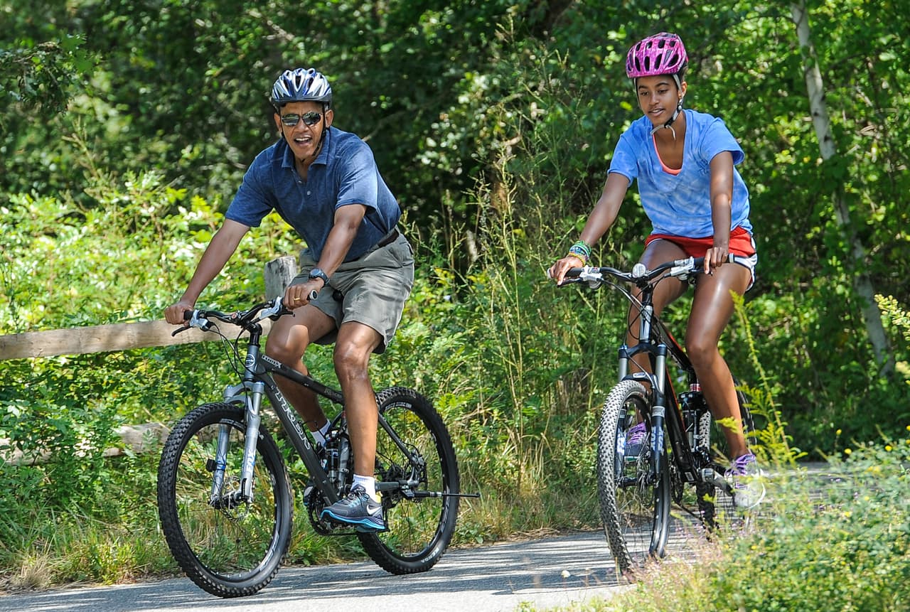 Barack Obama paseando en bicicleta con Malia en 2013. Sasha y Michelle Obama también les acompañaron ese día.
