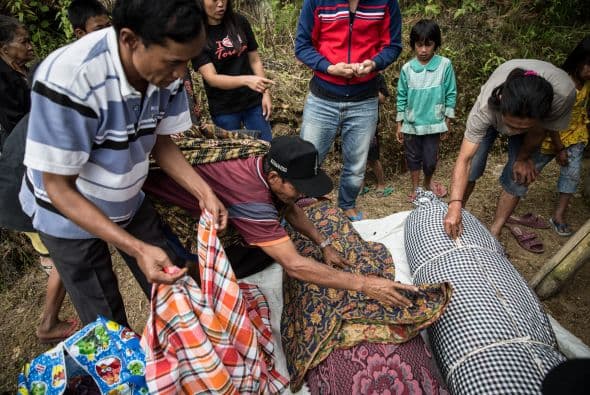 Familiares cubren un cuerpo sin vida durante el ritual de Manene en Indonesia. Cada tres años cambian la ropa a sus antepasados, que permanecen momificados en Barrupu Village.