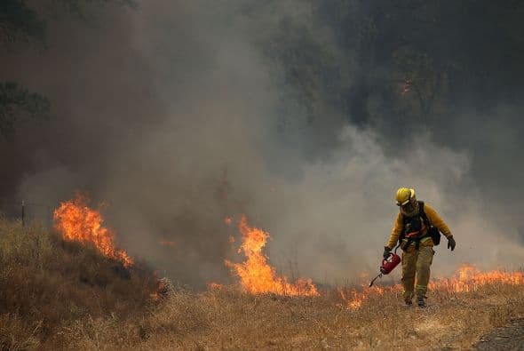 Un bombero quema la hierba seca durante una operación para extinguir el fuego en California.