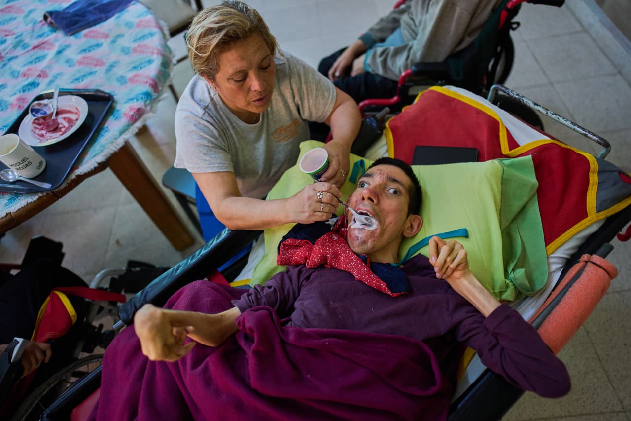 Nancy Bravo alimenta a Miguel Rojas in the Pequeño Cottolengo Don Orione.