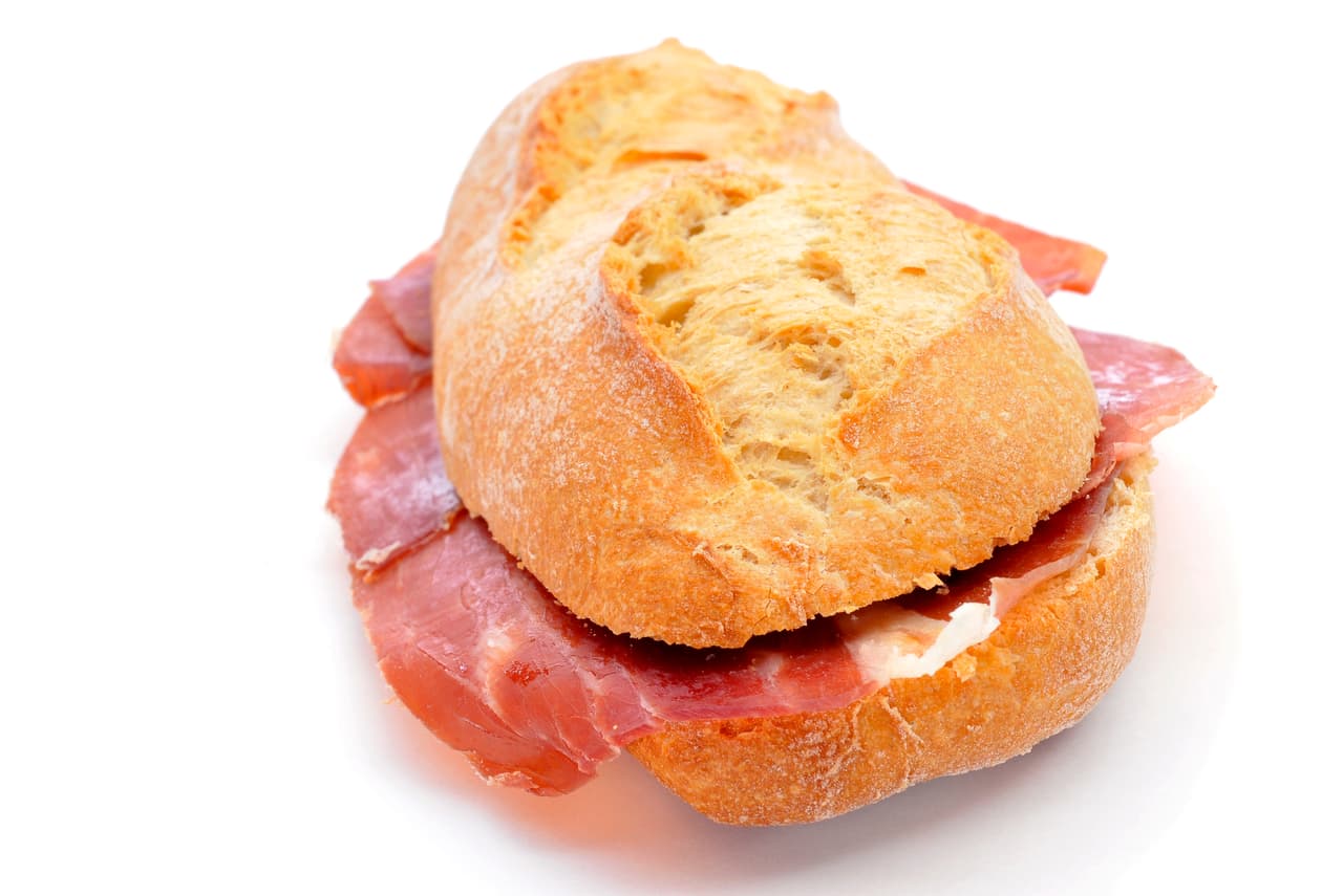 <b>Puesto 15. Bocadillo de jamón</b>
<br>
<br>El bocadillo de jamón se elabora con pan español y lonjas de jamón serrano o ibérico. Por lo general la barra de pan se corta por la mitad y se le coloca el jamón en capas.
<br>
<br>El lado interno de las mitades a menudo se rocía con aceite de oliva y se frota con tomate maduro y ajo para darle sabor y suavidad. Se puede realzar con rodajas de queso manchego, rodajas de tomate, tiras de pimientos del piquillo asados y aceitunas negras deshuesadas.
<br>