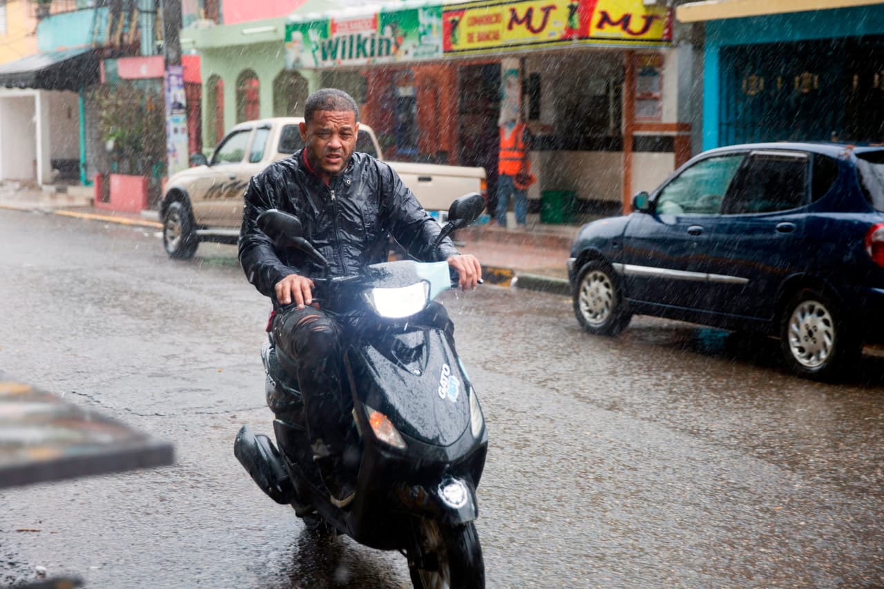 Un hombre conduce una motocicleta bajo una lluvia torrencial.