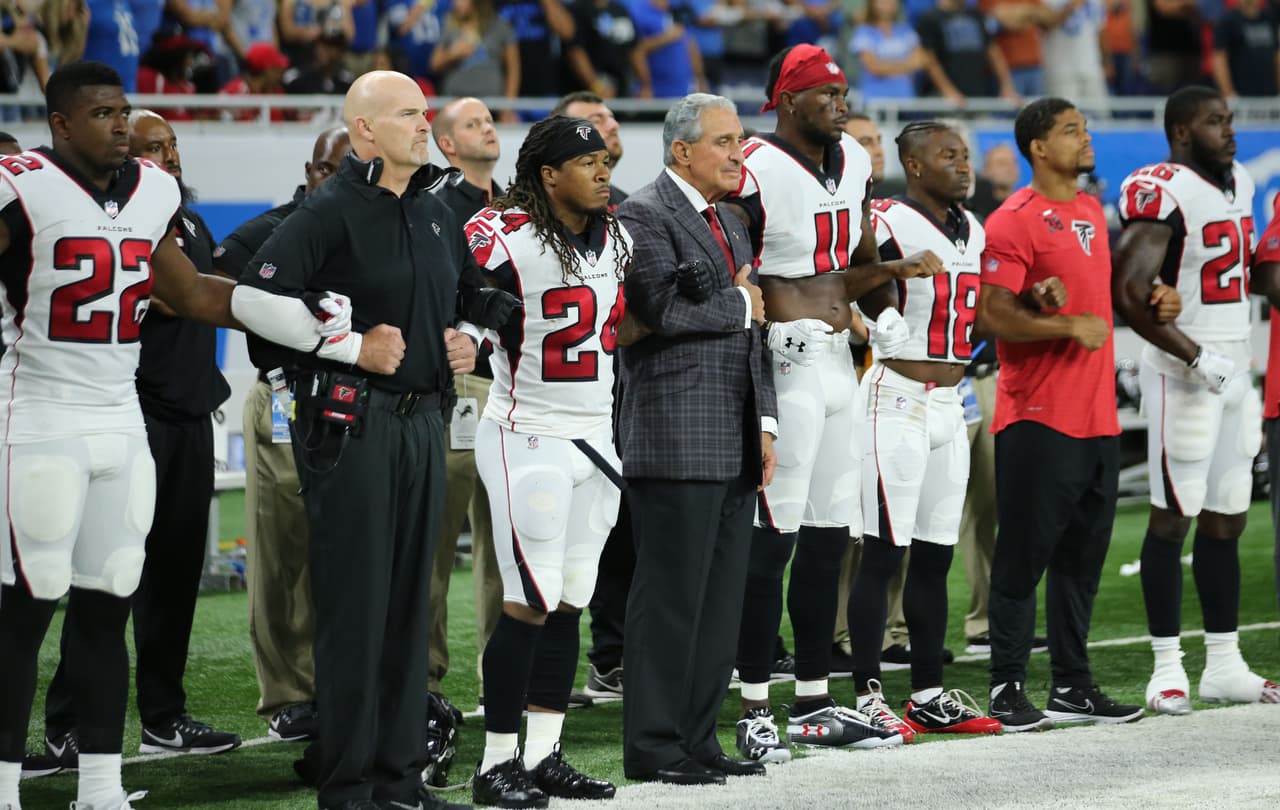 El dueño de los Atlanta Falcons, Arthur Blank, entrelaza sus brazos con los jugadores del equipo durante el himno nacional del partido ante los Detroit Lions.
<br>