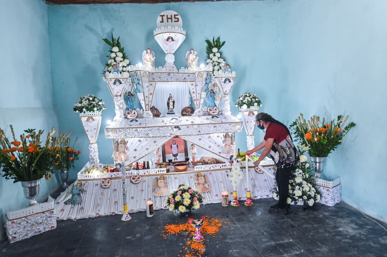 María Ricarda Castro enciende una vela en un Altar Monumental dedicado a su madre Teresa Blas, en Huaquechula, Puebla,