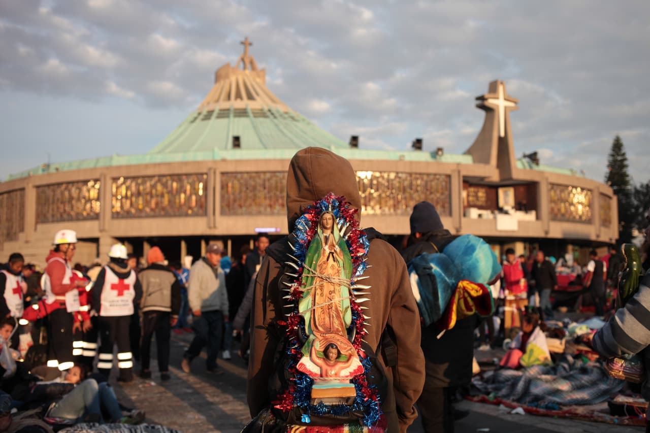 Un peregrino carga una imagen de la Virgen de Guadalupe mientras caminan rumbo al templo de la Basílica.