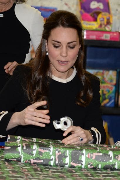 Con gran habilidad, Kate ponía cinta sobre el papel y sostenía la caja.