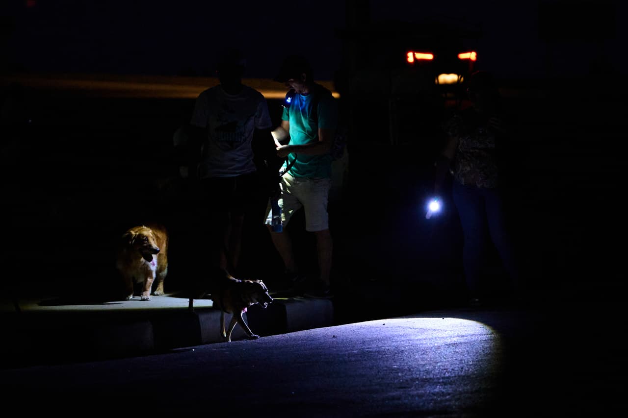 People walk their dogs using flashlights during a blackout in Havana, Cuba, Monday, July 6, 2026. (AP Photo/Ramon Espinosa)